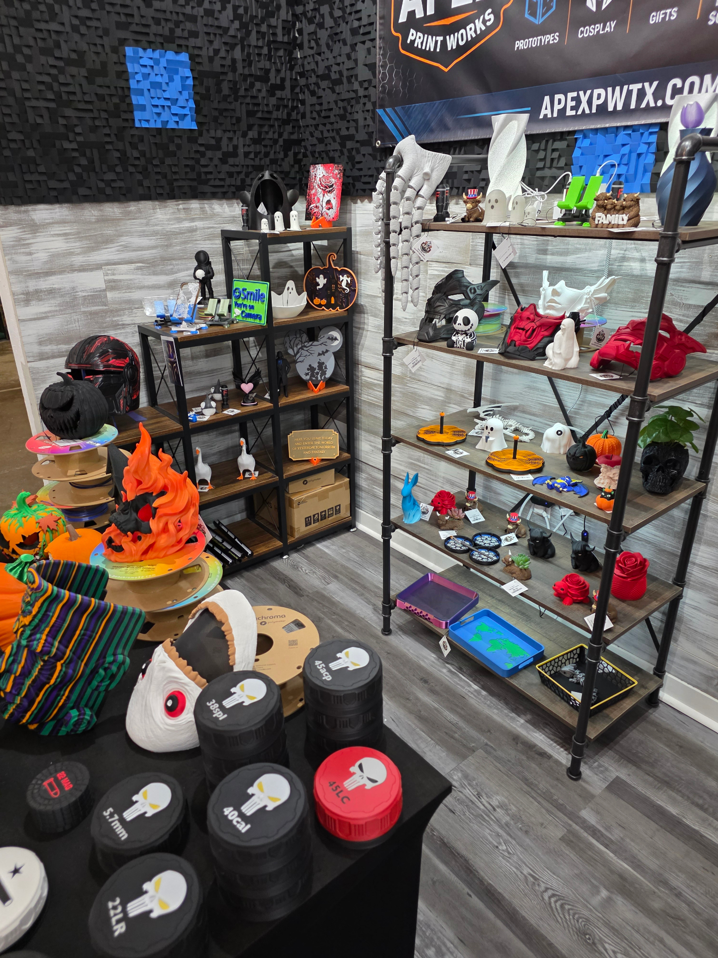 Apex Print Works booth shelves stocked with printed masks, helmets, pumpkins, and display pieces
