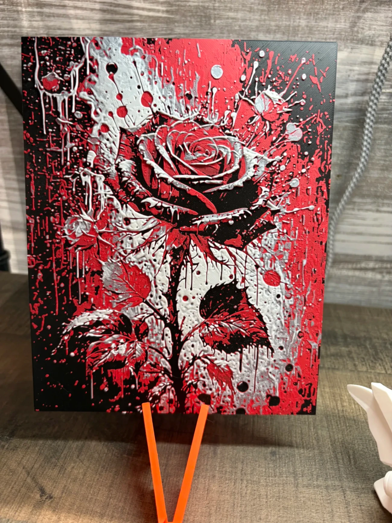 Textured wall panel of a red rose with white and black paint spatter
