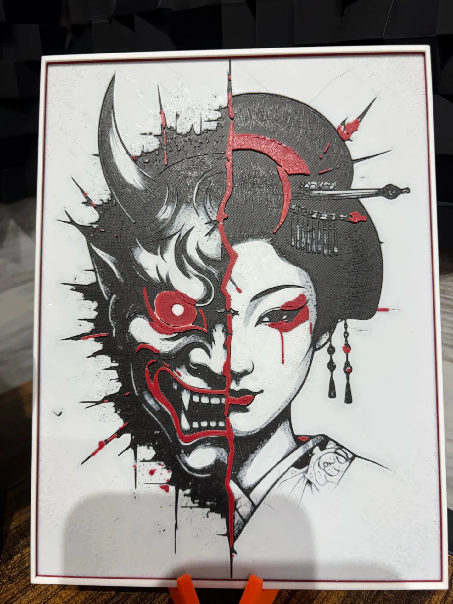 Layered panel of a split geisha and oni face in black, white, and red